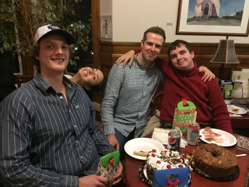 Four students smiling in front of food, presents, and drinks.