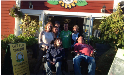 A group of students and faculty pose together outside of the Wolfville Farmer's Market.